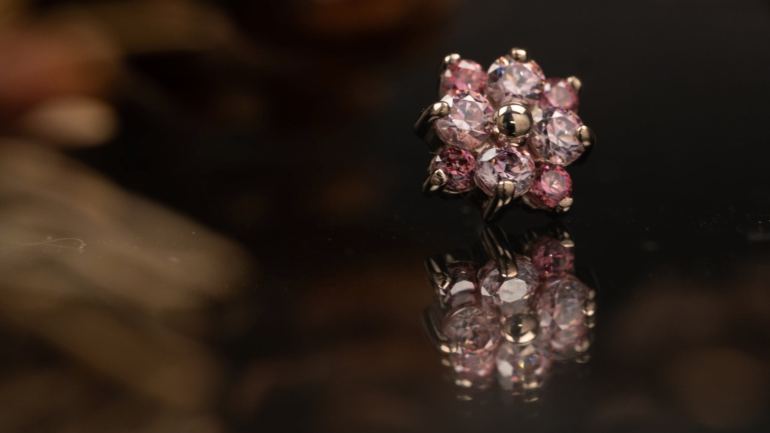 Pink gemstone ring with a blurred floral background
