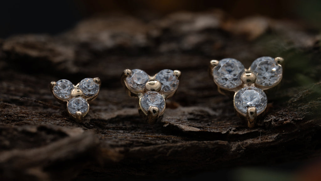 Three butterfly-shaped diamond earrings on a dark surface with a blurred background